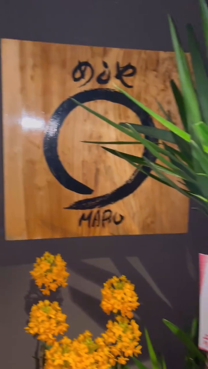 暗い壁に木の看板が掛かった、maruの入口の風景